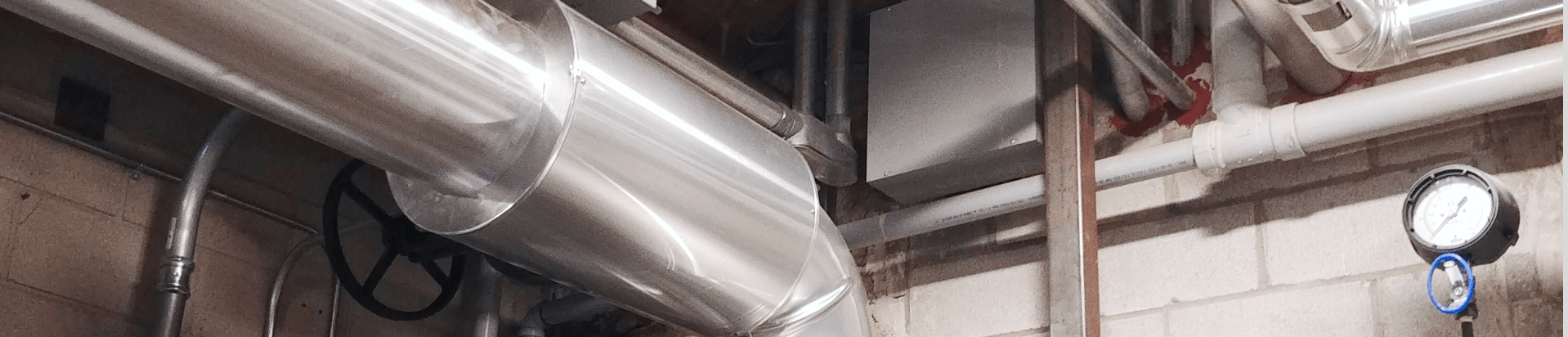 Metal jacketing over large-bore pipe insulation in a mechanical room.